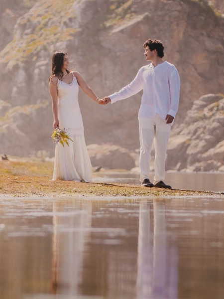 Sofía y Roberto de la mano junto a una laguna, con su reflejo en el agua